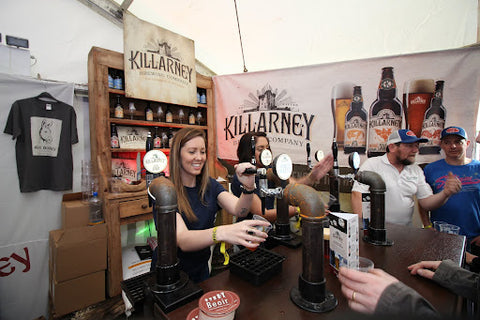 Beer festival tent, woman serving beer out of tap. 