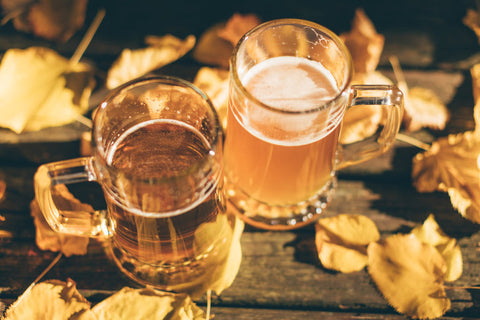 Two pints of beer on a fall leave covered table