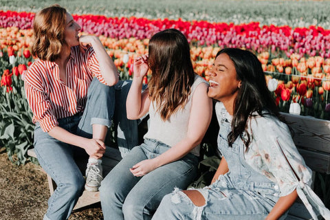 Three women on a bench in a field of colorful tulips. 